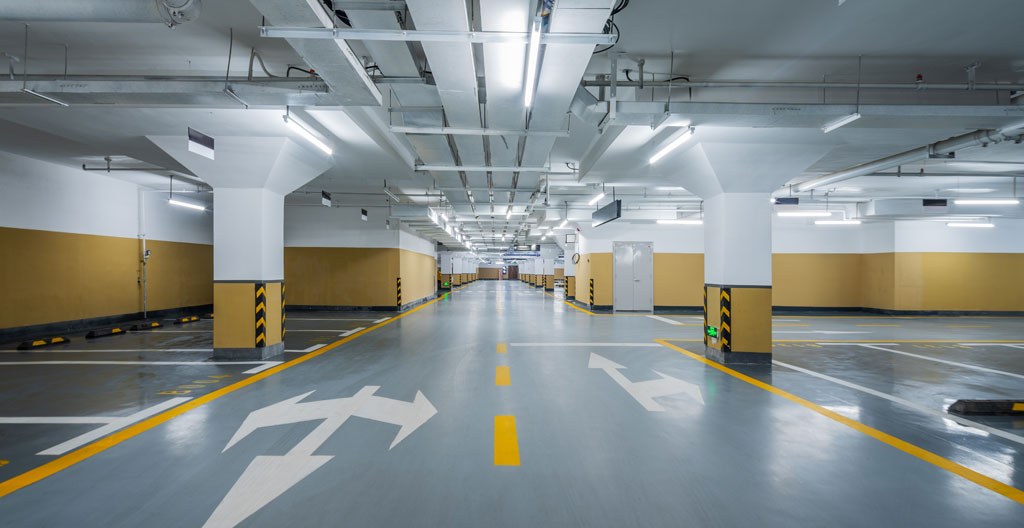 Chaîne rouillée et pancarte 'Défense de stationner' barrant l'entrée d'un box de parking.